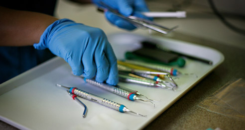 Closeup of dental hygienist selecting tools from a tray.